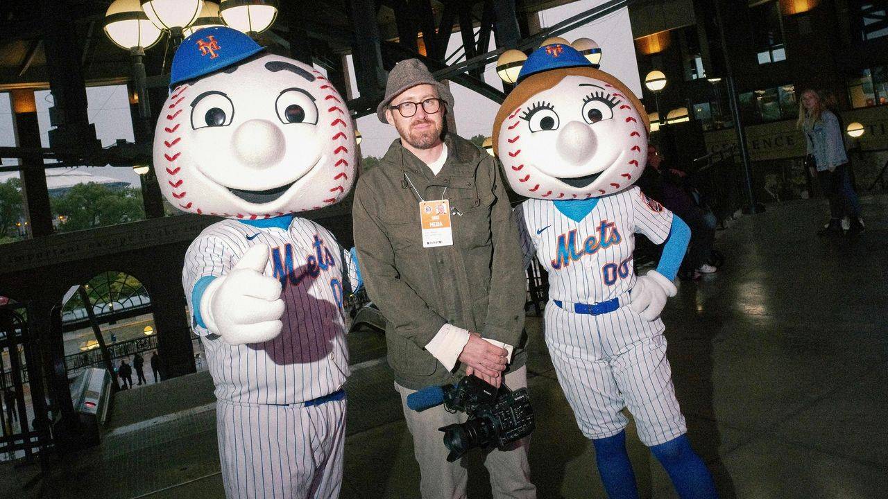 John Wilson standing between Mr. Met and Mrs. Met