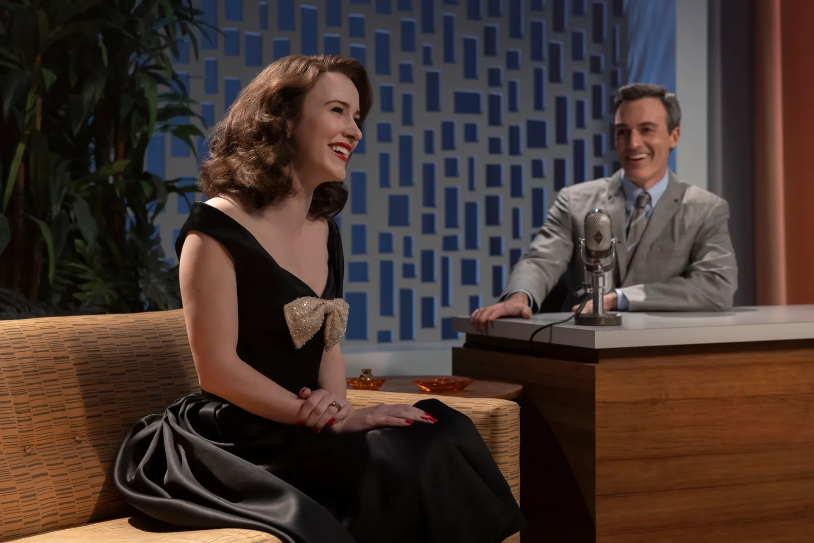 The Marvelous Mrs. Maisel: Miriam Maisel sitting on the couch at The Gordon Ford Show, with Gordon Ford at his desk