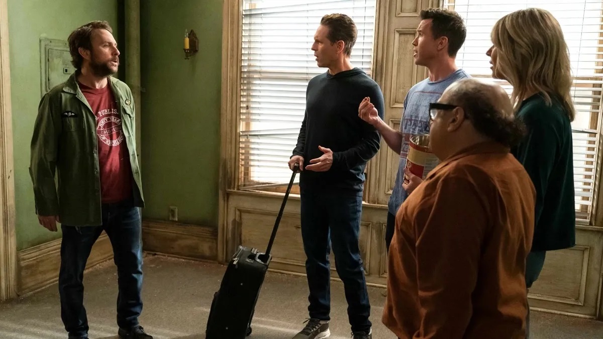 It's Always Sunny in Philadelphia: Charlie on the left facing Dennis, Mac, Dee, and Frank. Dennis is holding a roller suitcase.