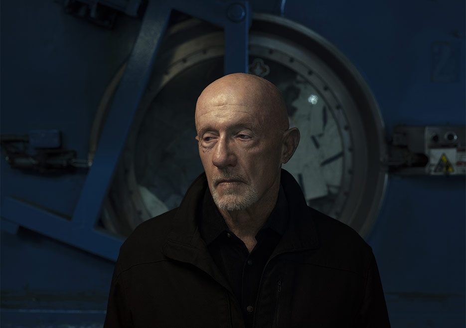 Mike Ehrmantraut (Jonathan Banks), standing in the industrial laundromat in front of one of the machines.