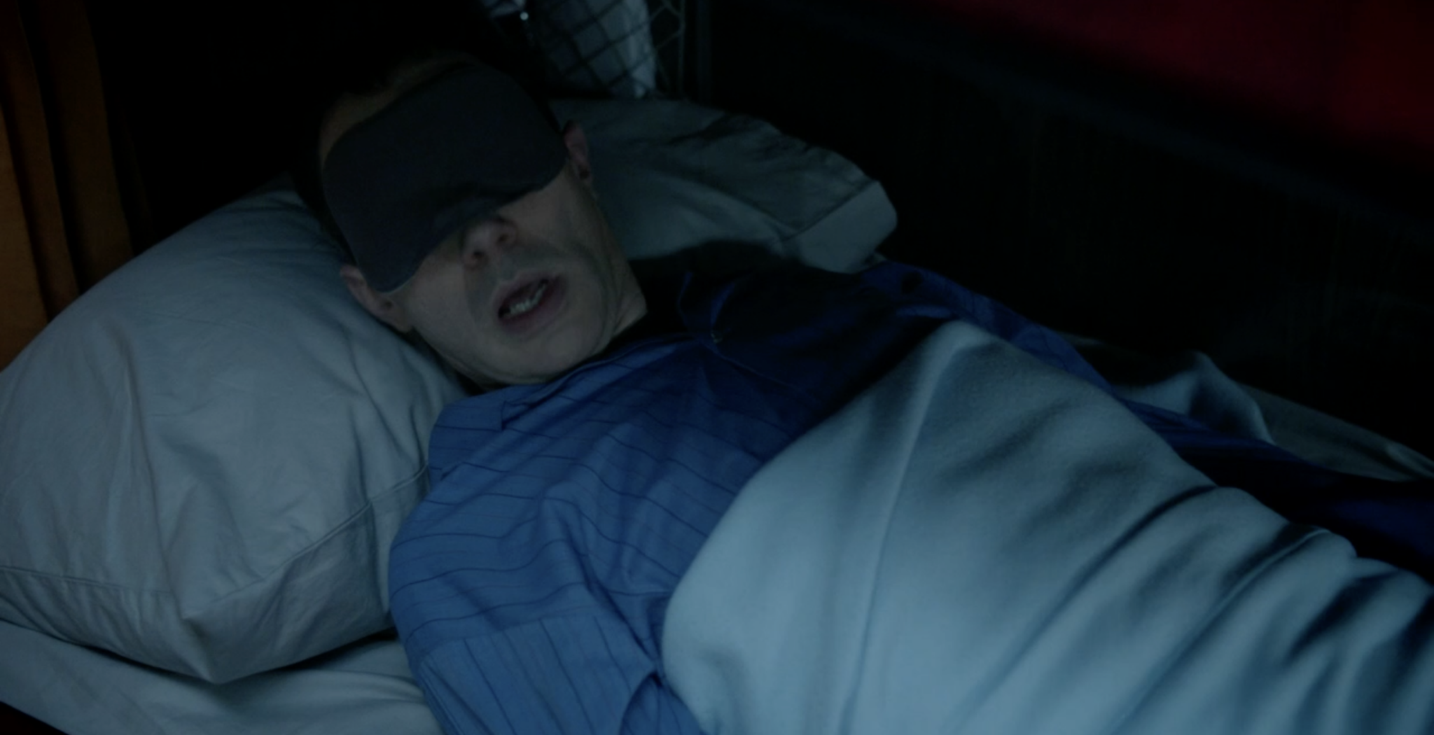 Maxwell, in a sleeping mask, is irritated to be woken up.